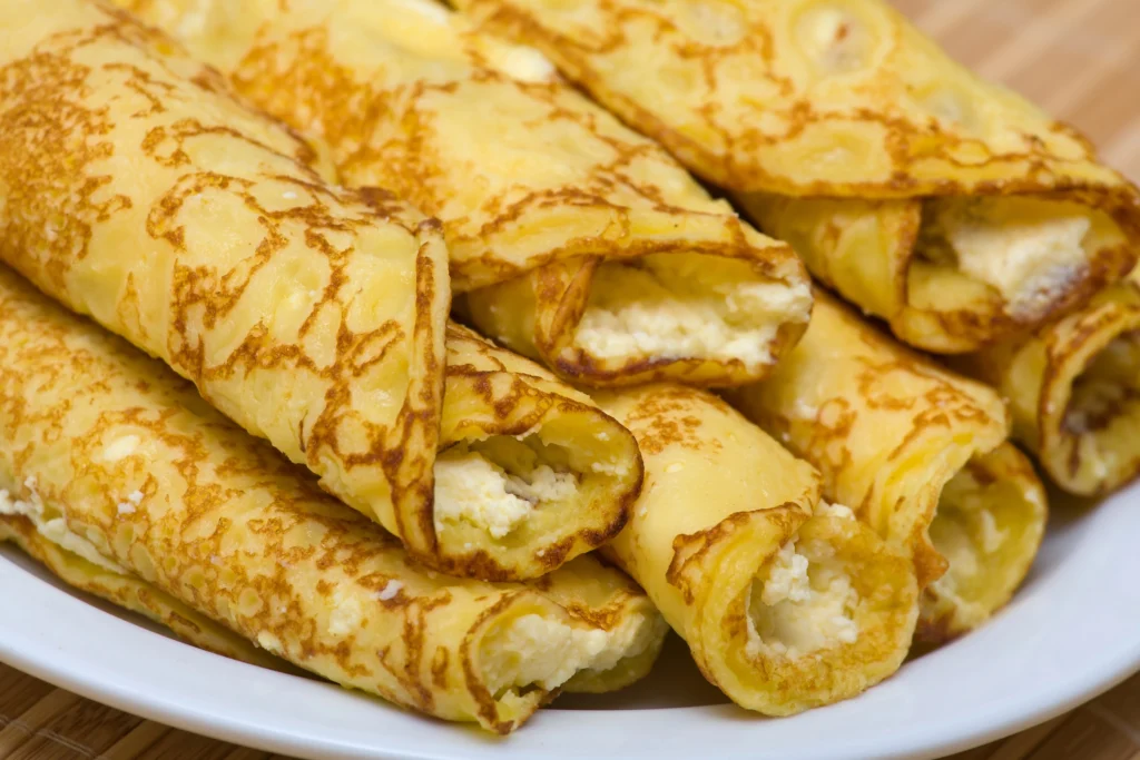 Hungarian Palacsinta crepes filled with sweet cottage cheese (túró) served stacked on white plate — classic cottage cheese pastry popular in Hungary.