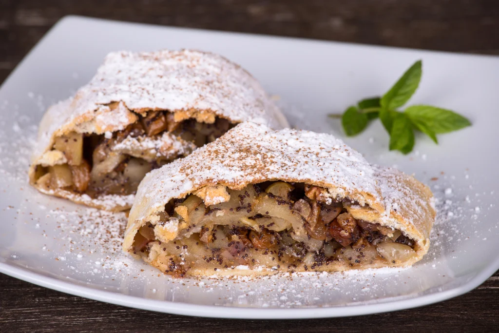 Hungarian apple and walnut strudel pastry (Rétes) sliced on plate with powdered sugar — traditional strudel pastry popular across Hungary.