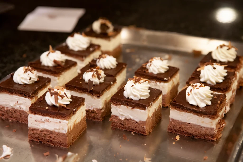 Hungarian Rigó Jancsi chocolate sponge cake cubes layered with rich chocolate buttercream and whipped cream topping — classic pastry shop dessert.