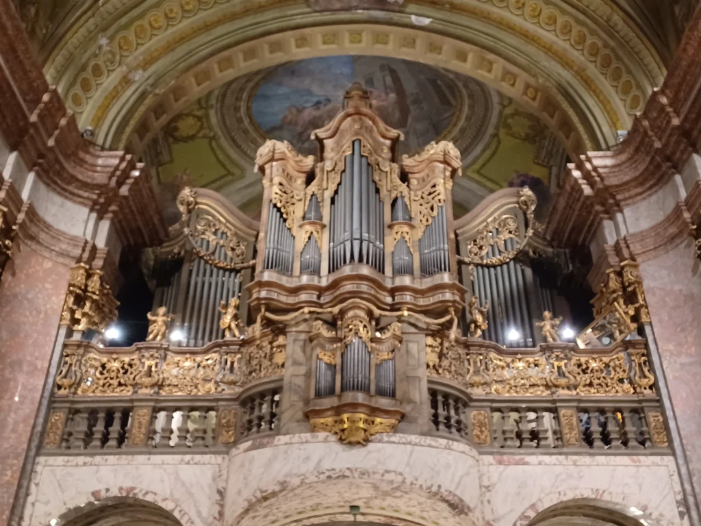 Ornate pipe organ inside the University Church in Budapest with decorative gold details and painted ceiling.