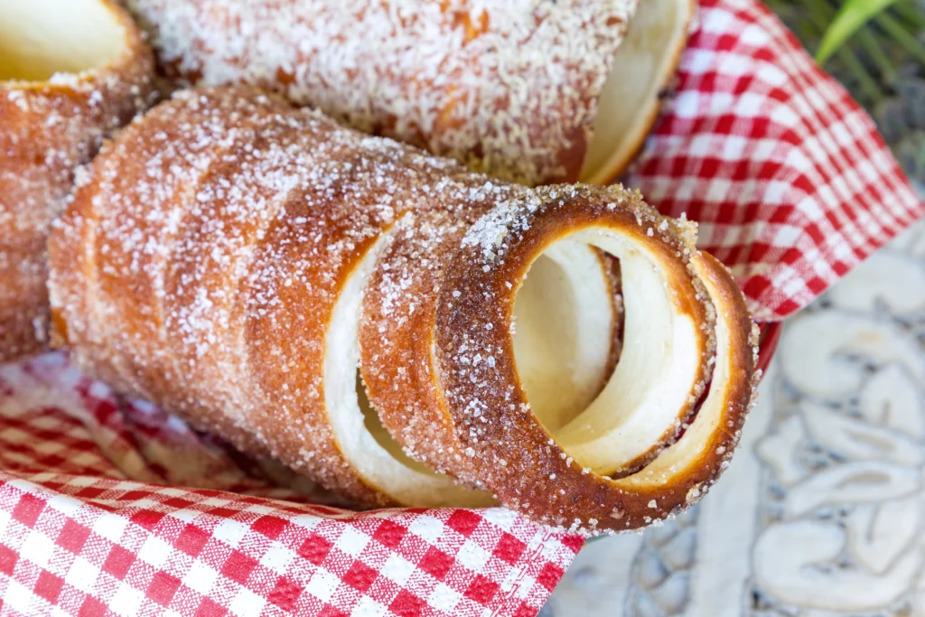 Hungarian Kürtőskalács Chimney Cake rolled in sugar and baked over coals — traditional sweet yeast pastry popular at Budapest markets.