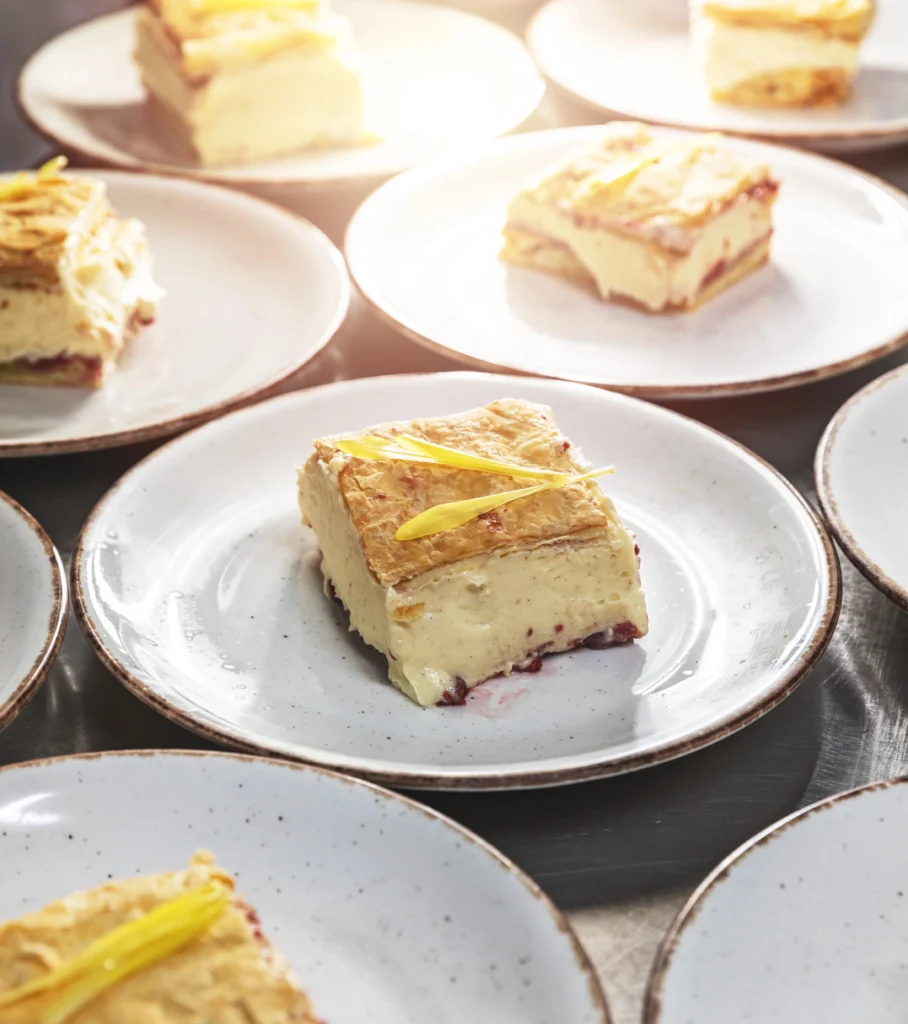 Hungarian Krémes custard slice pastry with flaky puff pastry base and vanilla cream filling served on white plates — classic dessert popular in Hungary.
