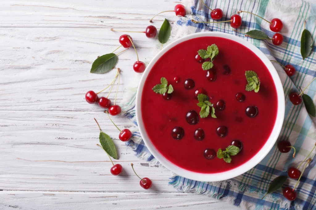 Hungarian Meggyleves cold sour cherry soup garnished with fresh cherries and mint — traditional summer dessert popular in Hungary.