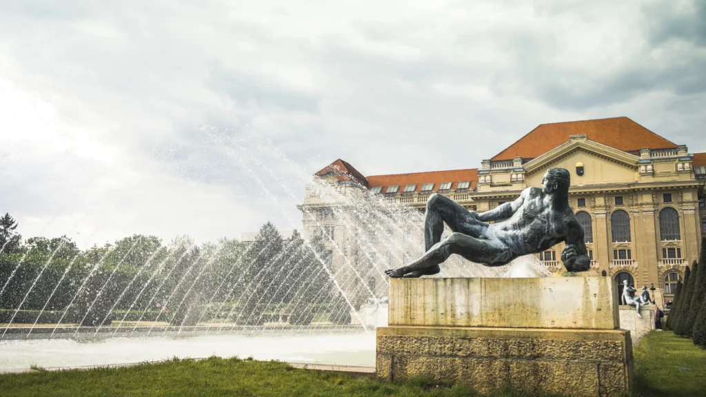 The University of Debrecen main building with fountain and reclining statue, a landmark of Hungary’s second-largest city and a center of education and culture.