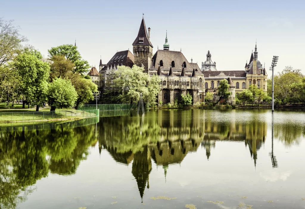 Vajdahunyad Castle reflected in the lake at City Park, Budapest, blending Gothic and Renaissance design in a fairy-tale setting surrounded by greenery.